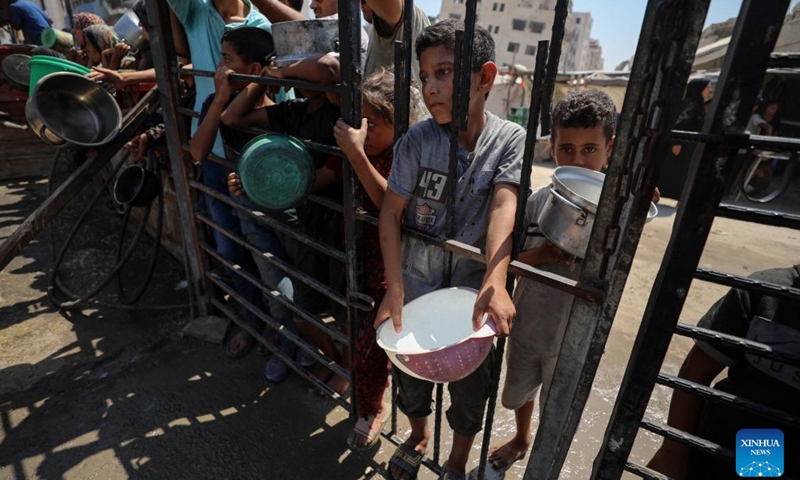 Palestinians wait to receive free food at a camp for displaced people in southwest Gaza City, on Aug. 24, 2025. (Photo by Rizek Abdeljawad/Xinhua)