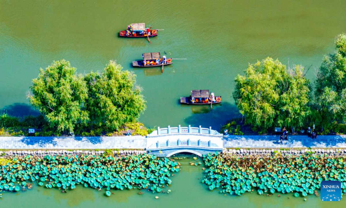 A drone photo taken on Oct. 7, 2025 shows tourists taking boats at the Lixiahe National Wetland Park in Xinghua City, east China's Jiangsu Province. Tourists across the country show no sign of fading enthusiasm as the National Day and Mid-Autumn Festival holiday draws to a close. (Photo by Zhou Shegen/Xinhua)