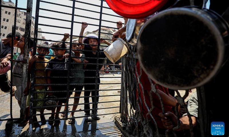 Palestinians wait to receive free food at a camp for displaced people in southwest Gaza City, on Aug. 24, 2025. (Photo by Rizek Abdeljawad/Xinhua)