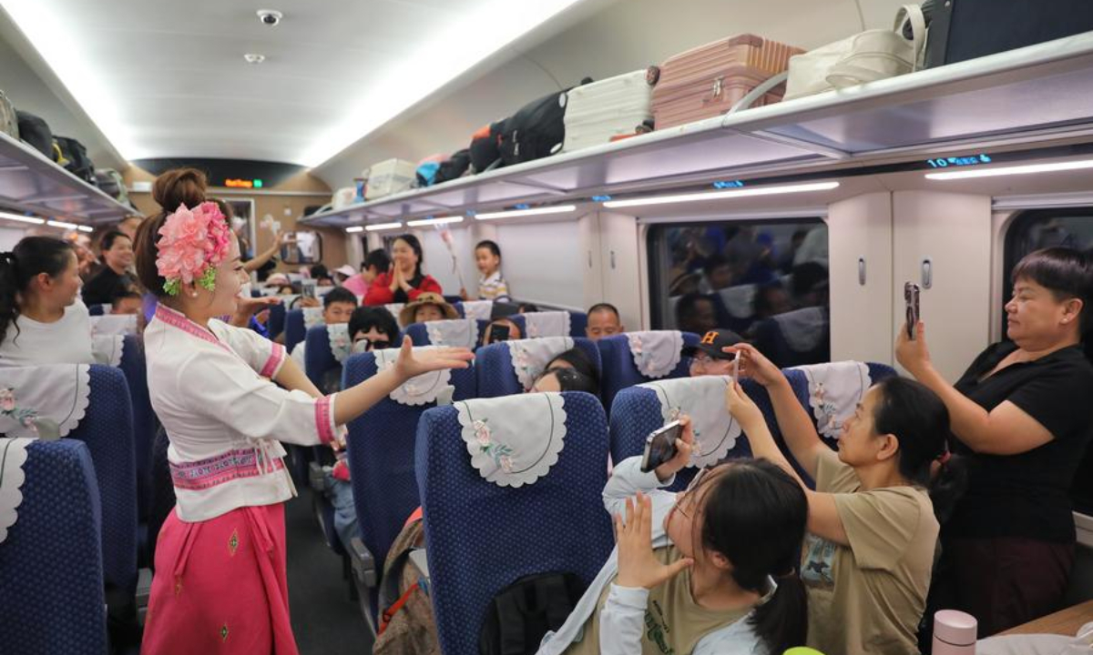 Stewardesses interact with passengers aboard train No. D86 from Kunming, capital city of southwest China's Yunnan Province, to the Lao capital Vientiane, July 18, 2025. (Photo by Yang Zixuan/Xinhua)