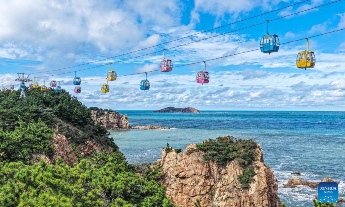 A drone photo taken on Oct. 7, 2025 shows tourists taking sightseeing cable cars at a scenic spot in Rongcheng, east China's Shandong Province. Tourists across the country show no sign of fading enthusiasm as the National Day and Mid-Autumn Festival holiday draws to a close. (Photo by Li Xinjun/Xinhua)