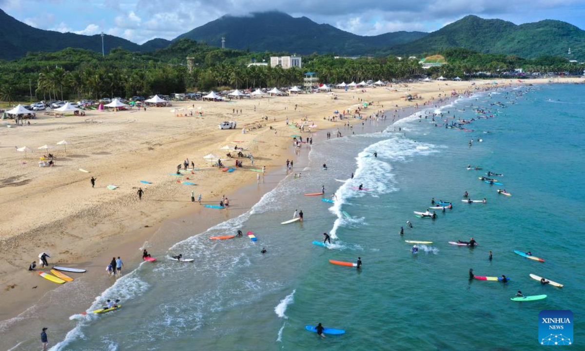An aerial drone photo shows tourists surfing at Riyue Bay in Wanning, south China's Hainan Province, Oct. 2, 2025. Surfing has become a symbol of Wanning thanks to its unique geographical and climatic advantages. (Xinhua/Guo Cheng)