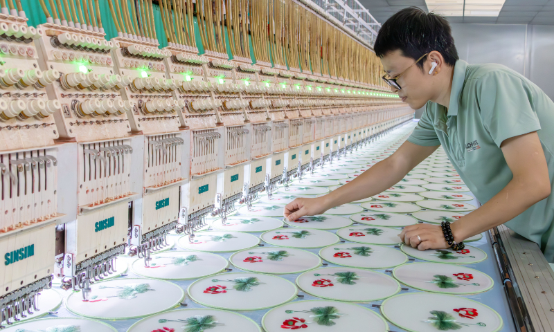 A worker inspects fan-shaped Suzhou embroidery-style products, crafted by automated machines, at a workshop in Xinyu, East China's Jiangxi Province, on September 16, 2025. Leveraging digitalization allows the two-thousand-year-old art of Suzhou embroidery to thrive on modern production lines. Suzhou embroidery is one of China's four major embroidery styles, with a history dating back more than 2,000 years. Photo: VCG