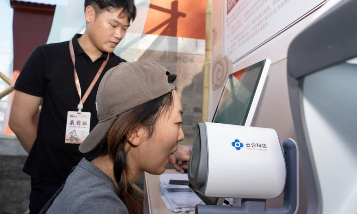 A visitor has her tongue checked by a medical examination device at the booth of the Anhui University of Traditional Chinese Medicine at a fair themed on traditional Chinese medicine (TCM) and culture in Xicheng District of Beijing, capital of China, Sept. 19, 2025. (Xinhua/Cai Yang)
