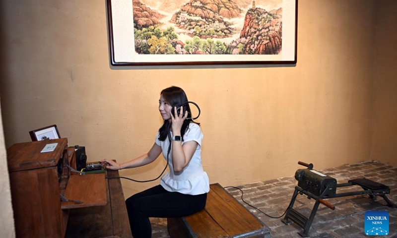 A visitor explore the models of a small telegraph transmitter and a hand-cranked motor used by Xinhua News Agency during its years in the revolutionary base of Yan'an, a city in northwest China's Shaanxi Province, at an art exhibition highlighting the Chinese People's War of Resistance Against Japanese Aggression in Beijing, capital of China, Aug. 26, 2025. (Xinhua/Jin Liangkuai)