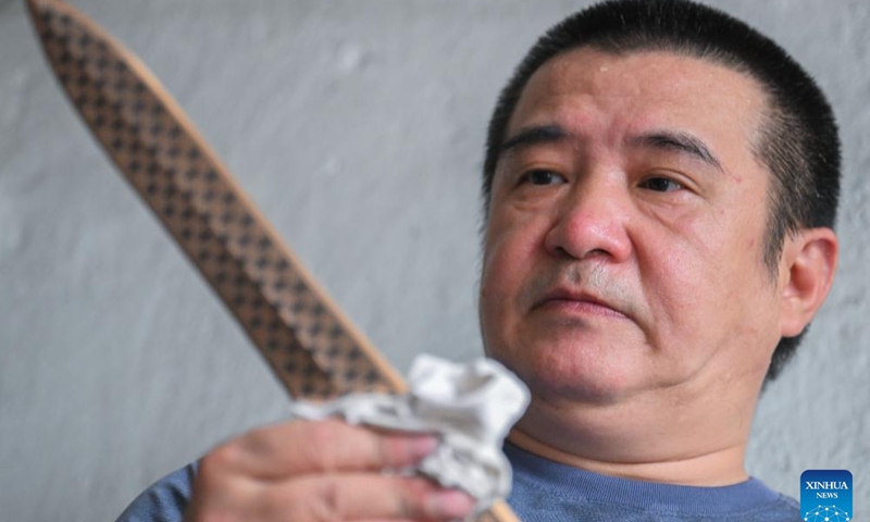 Ao Xinghua wipes a finished lead-tin engraving artwork at Ao's family workshop in Buhe Town of Jingzhou City, central China's Hubei Province, June 24, 2025.