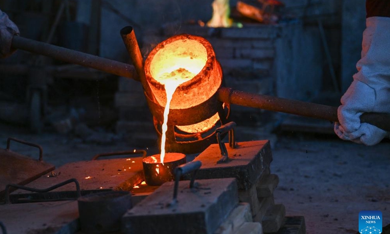 Ao Xinghua and his brother Ao Xingqiang pour molten copper into a mould at Ao's family workshop in Buhe Town of Jingzhou City, central China's Hubei Province, June 17, 2025.