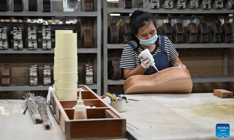 A worker makes a guitar at a workshop in Songzi City, central China's Hubei Province, Aug. 28, 2025. The guitar making industry has become the city's signature industry. (Xinhua/Du Zixuan)