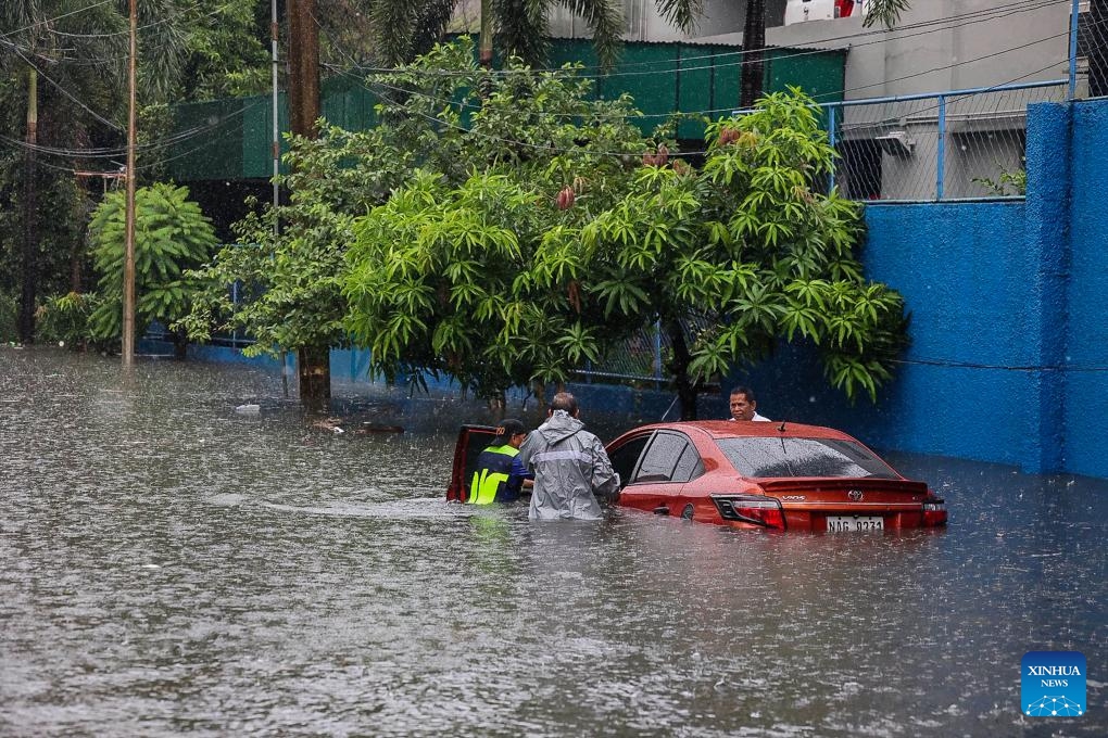 A car is seen partially submerged in floodwater at a street during a heavy rain in Quezon City, the Philippines, on Aug. 30, 2025. (Photo: Xinhua)