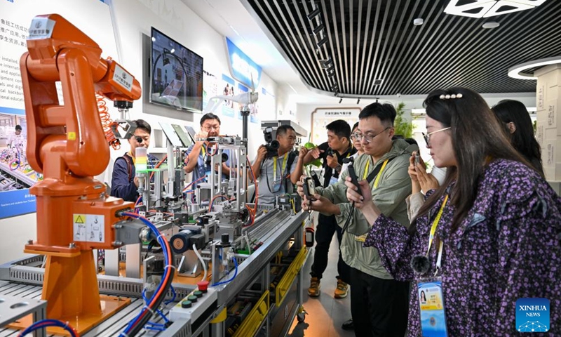 Journalists learn about the industrial robot training equipment at the Lu Ban Workshop Experience Museum of Tianjin Light Industry Vocational Technical College, in Tianjin, north China, on Aug. 30, 2025. Multiple city visiting events have been arranged in Tianjin by the media center of the Shanghai Cooperation Organization (SCO) Summit 2025 from Aug. 28 to Aug. 30, providing opportunities for Chinese and foreign journalists to learn about distinctive highlights in Tianjin's history and culture, its scientific and technological development, cultural and people-to-people exchanges, as well as other fields during their visits. (Photo: Xinhua)