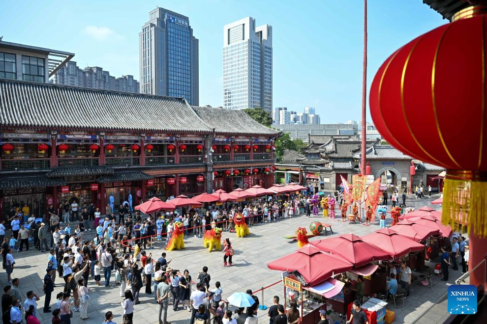 Journalists watch a lion dance performance with citizens at a square on the Tianjin Ancient Culture Street in Tianjin, north China, on Aug. 29, 2025. Multiple city visiting events have been arranged in Tianjin by the media center of the Shanghai Cooperation Organization (SCO) Summit 2025 from Aug. 28 to Aug. 30, providing opportunities for Chinese and foreign journalists to learn about distinctive highlights in Tianjin's history and culture, its scientific and technological development, cultural and people-to-people exchanges, as well as other fields during their visits. (Photo: Xinhua)