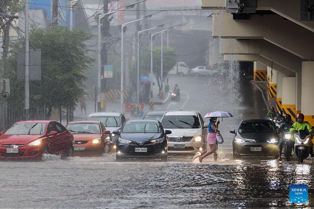 A woman crosses a street during heavy rain in Quezon City, the Philippines, on Aug. 30, 2025. (Photo: Xinhua)