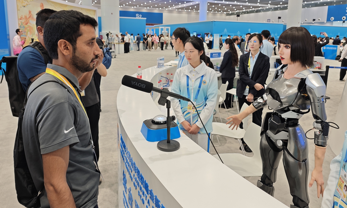A reporter interacts with a humanoid robot at the SCO Summit press center in Tianjin on August 31, 2025. Photo: Yin Yeping