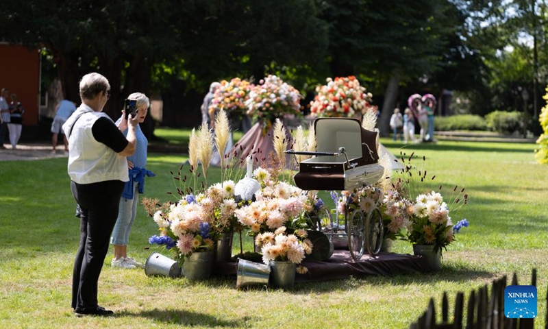 A visitor takes photos of a decoration made of dahlias at the garden of Keukenhof Castle during the Keukenhof Dahlia Days event in Lisse, the Netherlands, Aug. 30, 2025. The annual event is held here from Aug. 29 to 31. (Photo: Xinhua)