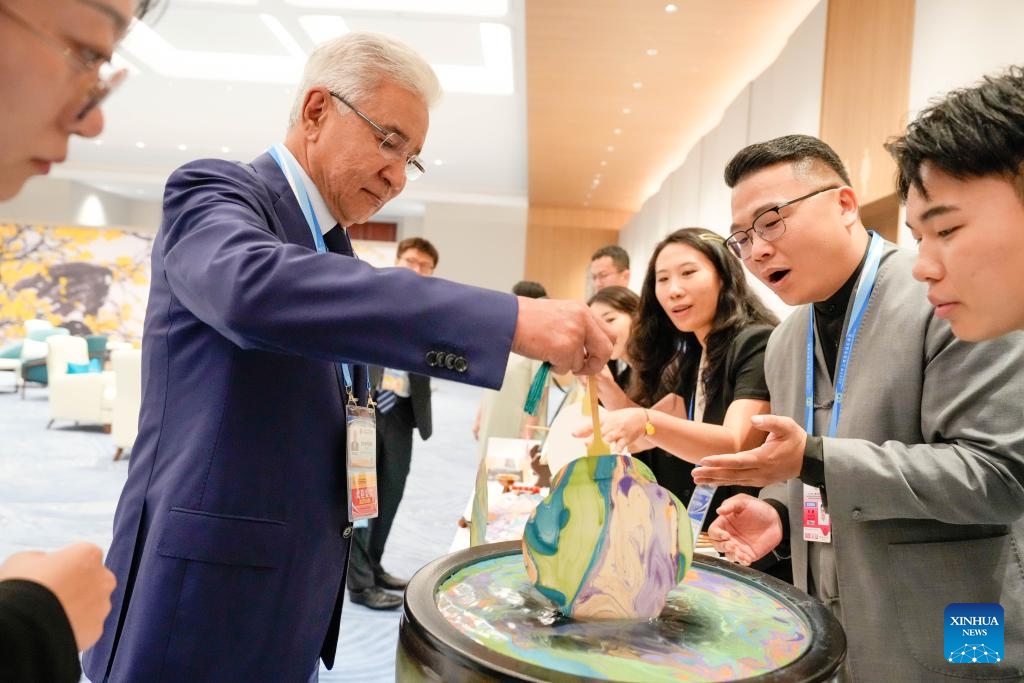 A guest tries lacquer fan crafting before a welcoming banquet at the Meijiang Convention and Exhibition Center in Tianjin, north China, Aug. 31, 2025. Chinese President Xi Jinping and his wife, Peng Liyuan, on Sunday hosted a banquet in China's port city of Tianjin to welcome international guests who are here to attend the Shanghai Cooperation Organization (SCO) Summit 2025. Before the banquet, the guests watched and experienced China's intangible cultural heritages, having friendly exchanges in a harmonious atmosphere. (Photo: Xinhua)