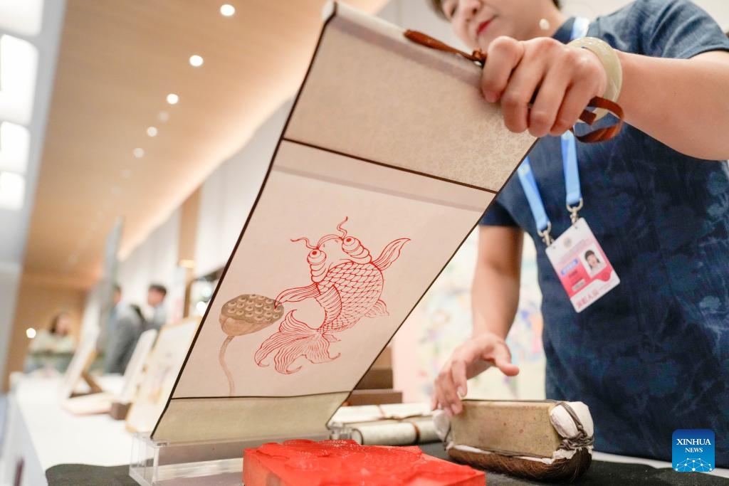 A staff member displays a Yangliuqing woodblock new year picture before a welcoming banquet at the Meijiang Convention and Exhibition Center in Tianjin, north China, Aug. 31, 2025. Chinese President Xi Jinping and his wife, Peng Liyuan, on Sunday hosted a banquet in China's port city of Tianjin to welcome international guests who are here to attend the Shanghai Cooperation Organization (SCO) Summit 2025. Before the banquet, the guests watched and experienced China's intangible cultural heritages, having friendly exchanges in a harmonious atmosphere. (Photo: Xinhua)