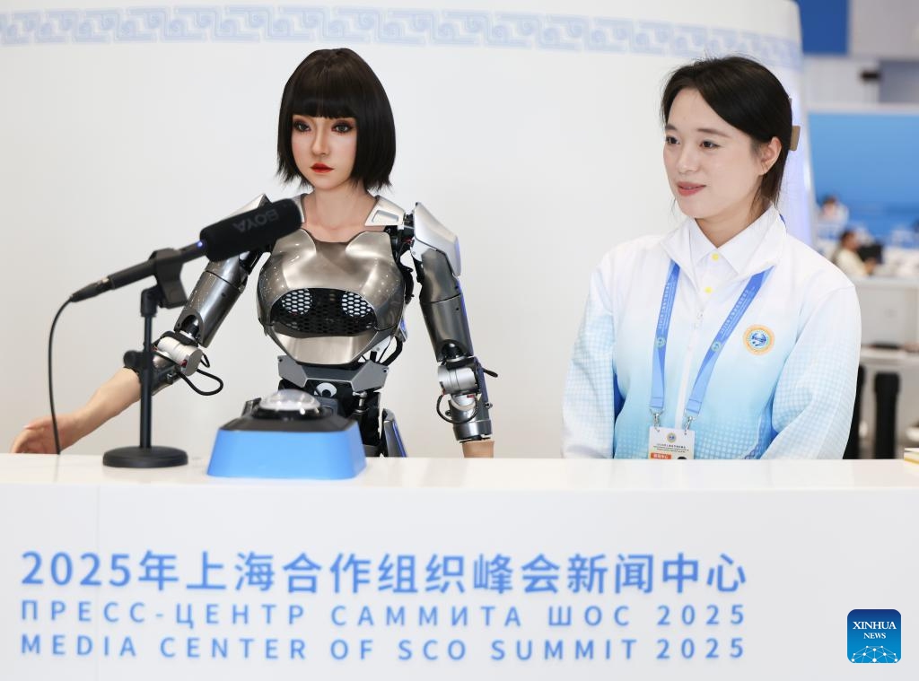 A volunteer welcomes guests with a multimodal interactive robot at the media center for the Shanghai Cooperation Organization (SCO) Summit 2025 in north China's Tianjin, on Aug. 29, 2025. The SCO Summit 2025 is held from Aug. 31 to Sept. 1 in Tianjin. A team of nearly 1,000 volunteers from local universities provide various service in areas like diplomatic etiquette, emergency response and language services to support the SCO Summit. (Photo: Xinhua)
