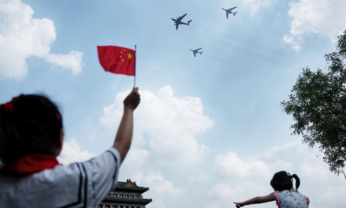 A child waves the Chinese national flag as planes fly overhead during the military parade in Beijing on September 3, 2025. Photo: Cui Meng/GT