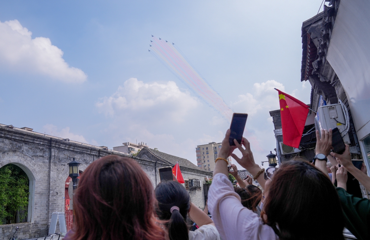 Residents gather in a hutong (traditional alleyways in central Beijing) to watch a formation of aircraft fly overhead during the military parade in Beijing on September 3, 2025. Photo: IC