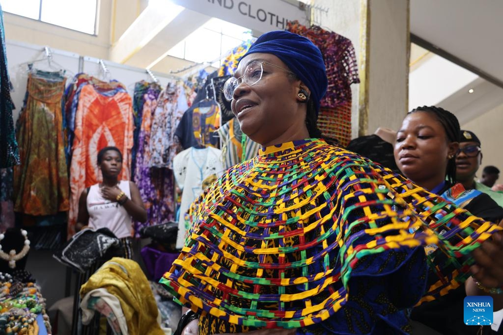 A visitor tries on a Ghanaian designer dress at the fourth Made-in-Ghana Bazaar in Accra, Ghana, Sept. 5, 2025. The three-day event opened here on Friday. (Photo: Xinhua)