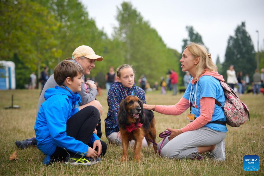 A volunteer introduces a dog to a family during an animal adoption event in Warsaw, Poland, on Sept. 7, 2025. The event organized by an animal shelter aims to familiarize the public with the adoption process and help sheltered animals find new homes. (Photo: Xinhua)