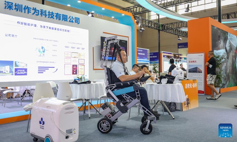 A visitor tries an intelligent walking assistance robot during the World Smart Industry Expo 2025 in southwest China's Chongqing Municipality, Sept. 5, 2025. The World Smart Industry Expo 2025 kicked off on Friday in southwest China's Chongqing Municipality, showcasing advanced achievements including AI rehabilitation systems, portable wearable devices, elderly care robots, and senior-friendly equipment. (Photo: Xinhua)