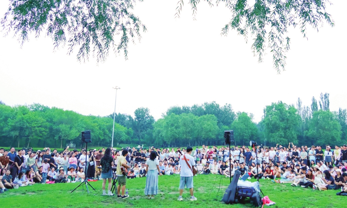 Audience members relax on the grass of Sun Park in Beijing, waiting for a new round of 