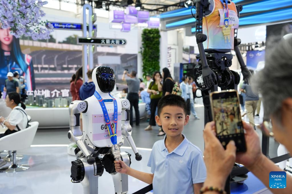 A kid poses for a photo with an award-winning robot at the 2025 China International Fair for Trade in Services (CIFTIS) at Shougang Park in Beijing, capital of China, Sept. 13, 2025. At the 2025 CIFTIS, a variety of cutting-edge technologies have enriched the exhibition, providing more interactive and immersing cultural and tourism experiences for visitors. (Photo: Xinhua)