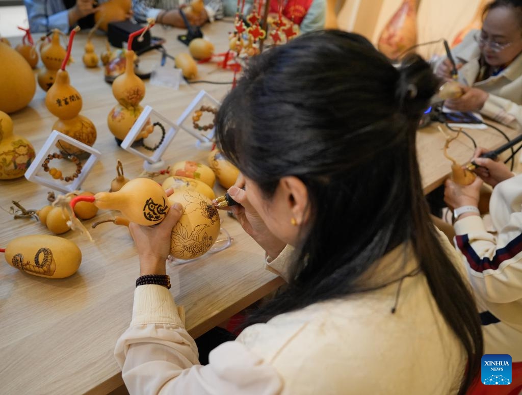 Traditional culture enthusiasts make gourd pyrography works at the Emin County memory museum in Emin County, northwest China's Xinjiang Uygur Autonomous Region, Sept. 13, 2025. While showcasing multi-ethnic culture and local history of the county, the museum has attracted many artisans and traditional culture lovers for handicraft exchange. (Photo: Xinhua)