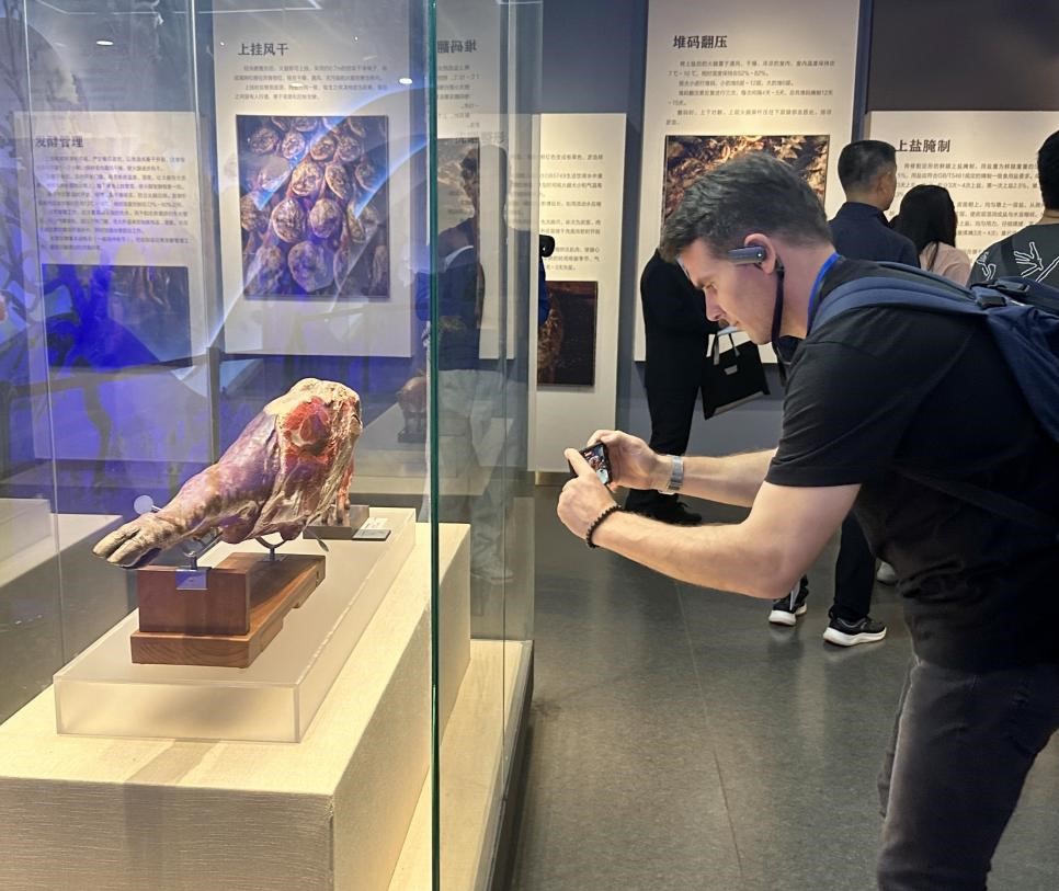 Marko Nedeljkovi?, a board member of the Journalists’ Association of Serbia, visits the Xuanwei Ham Exhibition Hall in Xuanwei, Yunnan Province, on September 20, 2025. Yunnan's Xuanwei ham, known for its rich flavor and aroma, is driving local growth. The ham-making technique of Xuanwei was listed as a national intangible cultural heritage in 2011. On September 20, 2025, foreign journalists experienced its unique taste and impact firsthand. (Photos: People's Daily/Lin Zihan)