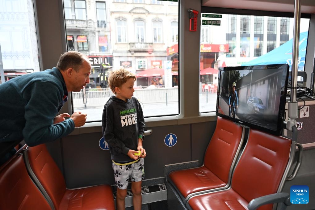 A parent and child watch a cycling safety video on a road safety awareness bus parked at a square during Car Free Sunday in Brussels, Belgium, Sept. 21, 2025. Brussels held its annual Car-Free Sunday this weekend, turning most streets of the Belgian capital into car-free zones for the day. From 9:30 a.m. to 7 p.m. local time on Sunday, motor vehicles were banned throughout the Brussels Region, with the exception of public transport, taxis, emergency services, police, and persons with a special permit. (Photo: Xinhua)
