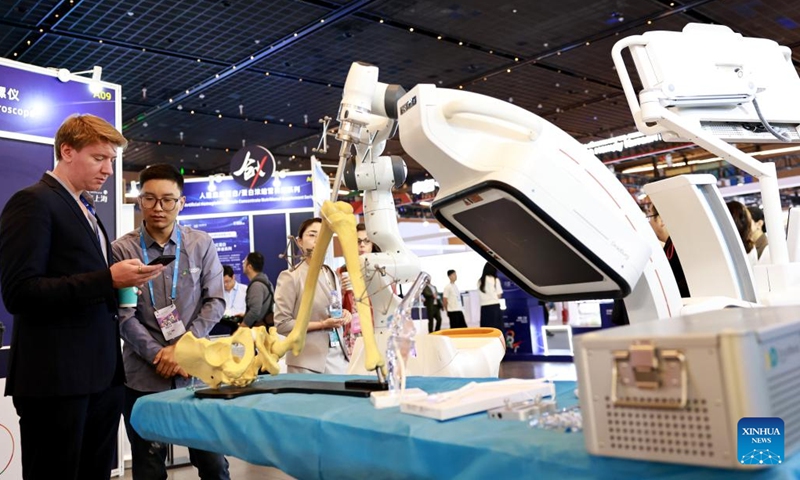 A staff member (2nd L) speaks with a visitor at the 2025 Pujiang Innovation Forum held in east China's Shanghai, Sept. 21, 2025. Co-hosted by China's Ministry of Science and Technology and the Shanghai municipal government, the 2025 Pujiang Innovation Forum was held here from Sept. 20 to 22. The forum, under the theme of Sharing Innovation and Shaping the Future: Building An Open and Cooperative Global Sci-tech Community, gathers over 500 guests from 45 countries and regions. (Photo: Xinhua)