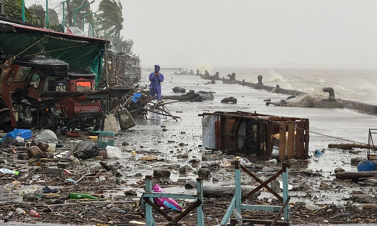 A man stands near debris on a waterfront road amid heavy rain due to weather patterns from Super Typhoon Ragasa in Aparri town, Cagayan province, Philippines on September 22, 2025. Photo: VCG