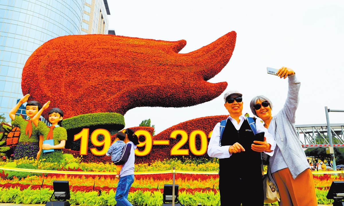 A couple takes a photo in front of one of 10 flower installations renewed for National Day alongside Chang'an Avenue in Beijing on September 23, 2025. Photo: VCG
