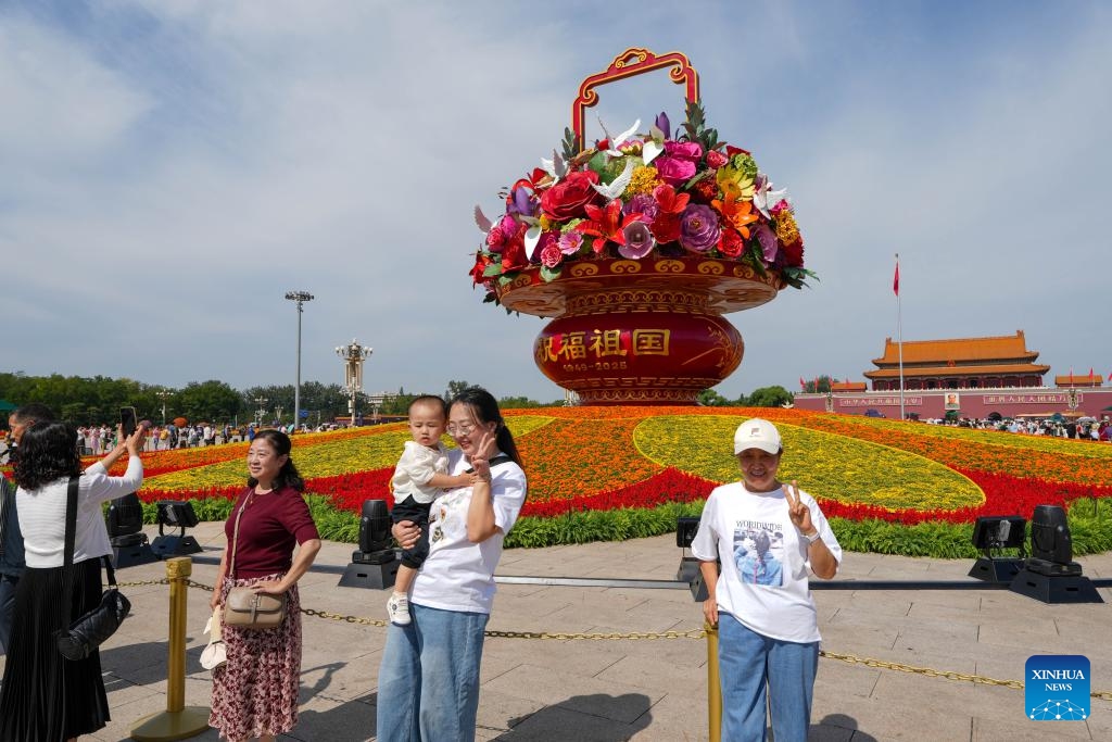 Tourists view a flower basket installation at Tian'anmen Square in Beijing, capital of China, Sept. 25, 2025. The 18-meter-high installation in the shape of a flower basket is placed at Tian'anmen Square as a decoration for the upcoming National Day holiday. (Xinhua/Ju Huanzong)

