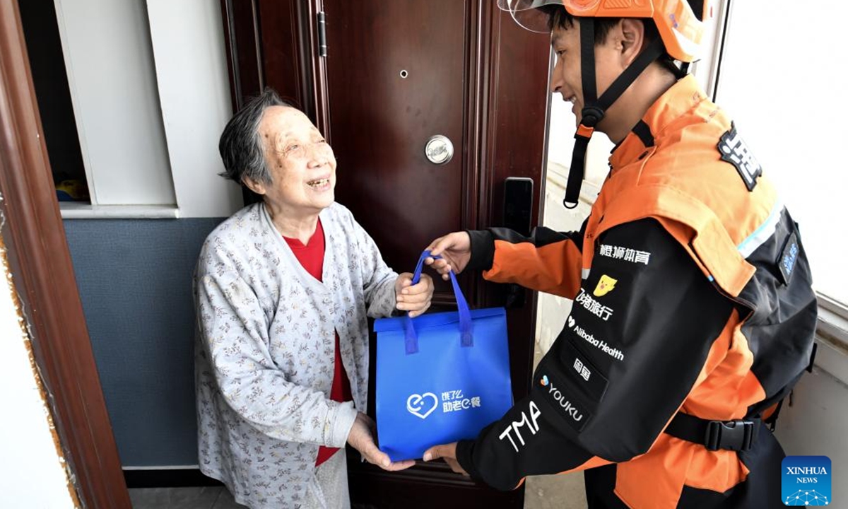 A deliveryman delivers meal for a senior woman in Xiangheyuan Neighborhood, Chaoyang District, Beijing, capital of China, Sept. 26, 2025. In recent years, Xiangheyuan Neighborhood of Chaoyang District has been actively developing a senior-friendly meal service network to meet the dietary needs of its elderly residents. The neighborhood has built two central kitchens and seven senior community canteens. Additionally, it has established a special meal delivery system for the elderly jointly with online platforms, ensuring that the elderly residents here can enjoy healthy and delicious meals. (Xinhua/Li Xin)

