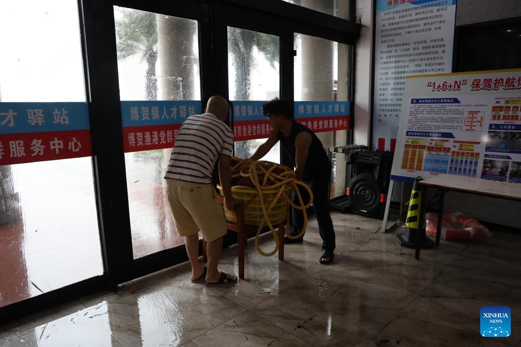 Staff members pile heavy items behind the entrance door to hold it against strong wind at a fishing harbor in Maoming City of south China's Guangdong Province, on Oct. 5, 2025. 