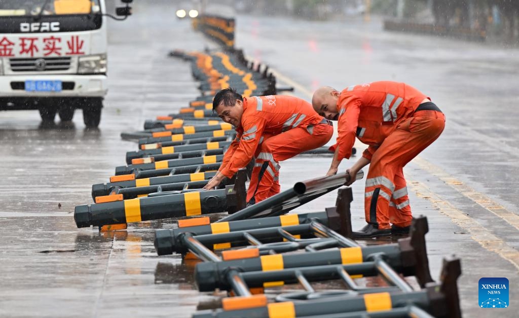 Staff members remove lane dividers pushed over by strong gusts in a street in Haikou, south China's Hainan Province, on Oct. 5, 2025. Typhoon Matmo, the 21st named storm of the 2025 Pacific typhoon season, is intensifying as it nears south China's coastal areas, leading to large-scale evacuations. The island province of Hainan has relocated over 197,000 people from high-risk areas as of Sunday noon, with a typhoon red alert remaining in effect. (Xinhua/Guo Cheng)