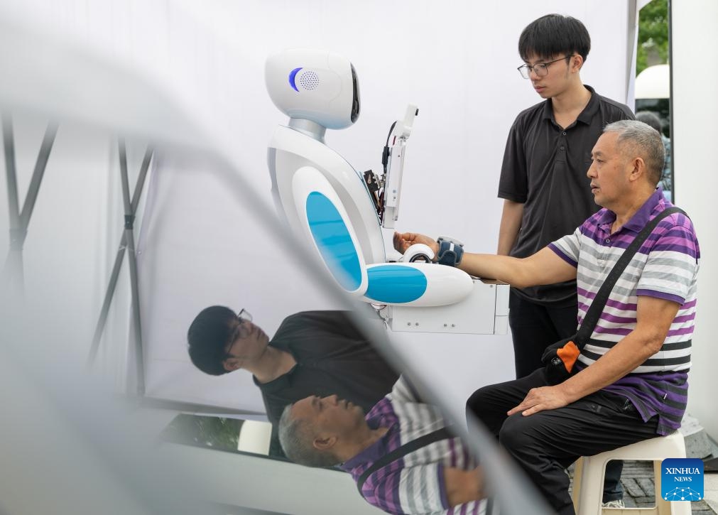 A citizen experiences diagnosis and treatment services provided by a mobile traditional Chinese medicine (TCM) intelligent robot at the Traditional Chinese Medicine Street in Bishan District, southwest China's Chongqing Municipality, Sept. 30, 2025. The Traditional Chinese Medicine Street, a cultural block featuring traditional Chinese medicine, opened to public on Tuesday. Characteristic cultural fairs, free TCM clinics, and Qigong performances will be held here during the upcoming National Day holiday and the Mid-Autumn Festival. (Xinhua/Chen Cheng)