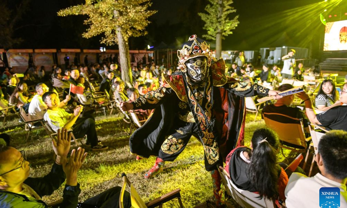 An artist performs Bianlian, or face-changing, a part of the Sichuan opera, at a forest camp in an industrial park in Chengdu, southwest China's Sichuan Province, Oct. 1, 2025. With China's Mid-Autumn Festival falling alongside National Day this year, people spend their leisure time through various ways during the eight-day holiday. (Photo by Li Xiangyu/Xinhua)

