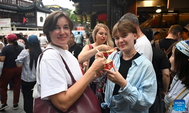 Tourists from Russia taste snacks at Yuyuan Garden Mall in east China's Shanghai, Oct. 3, 2025. The eastern Chinese megacity of Shanghai received a whopping 4.1 million overseas visitors from January to August this year.(Xinhua/Chen Haoming)