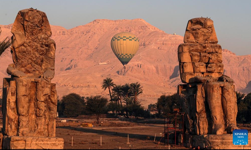 A hot air balloon is pictured near the Colossi of Memnon on the west bank of Nile River in Luxor, Egypt, on Oct. 4, 2025. Luxor, a capital of ancient Upper Egypt known as Thebes, is a tourist destination famous for the historic temple buildings and other relics. Nowadays taking hot air balloon trips is a popular choice for tourists visiting Luxor. (Xinhua/Ahmed Gomaa)