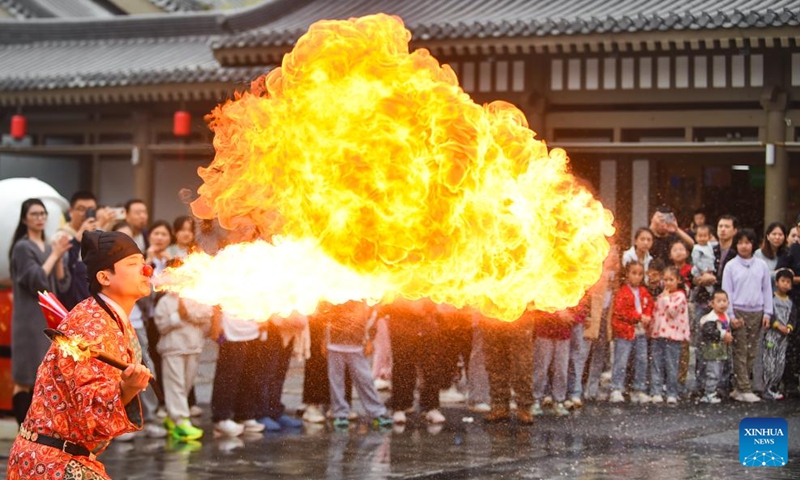 A fork artist performs for tourists at an ancient street scenic spot in Luolong District of Luoyang, central China's Henan Province, Oct. 5, 2025. Tourist destinations across China are witnessing a surge in visitors as the country's eight-day National Day and Mid-Autumn Festival holiday began on Wednesday. Photo: Xinhua