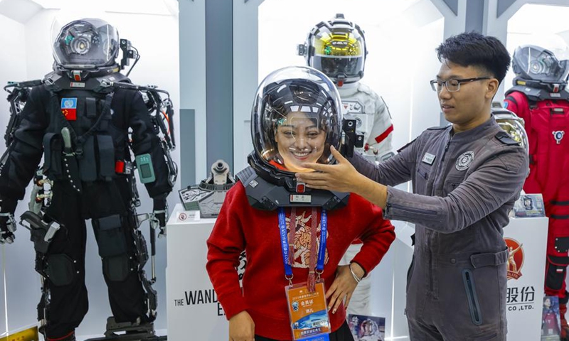 A visitor tries a space helmet originating from The Wandering Earth, a Chinese sci-fi blockbuster, during the 81st World Science Fiction Convention (WorldCon) in Chengdu, southwest China's Sichuan Province, Oct. 18, 2023. (Xinhua/Shen Bohan)