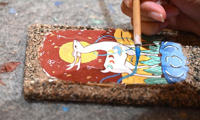 A tourist learns to draw mural patterns at a Dunhuang culture experience center in Dunhuang, northwest China's Gansu Province, Oct. 4, 2025. (Photo by Zhang Xiaoliang/Xinhua)