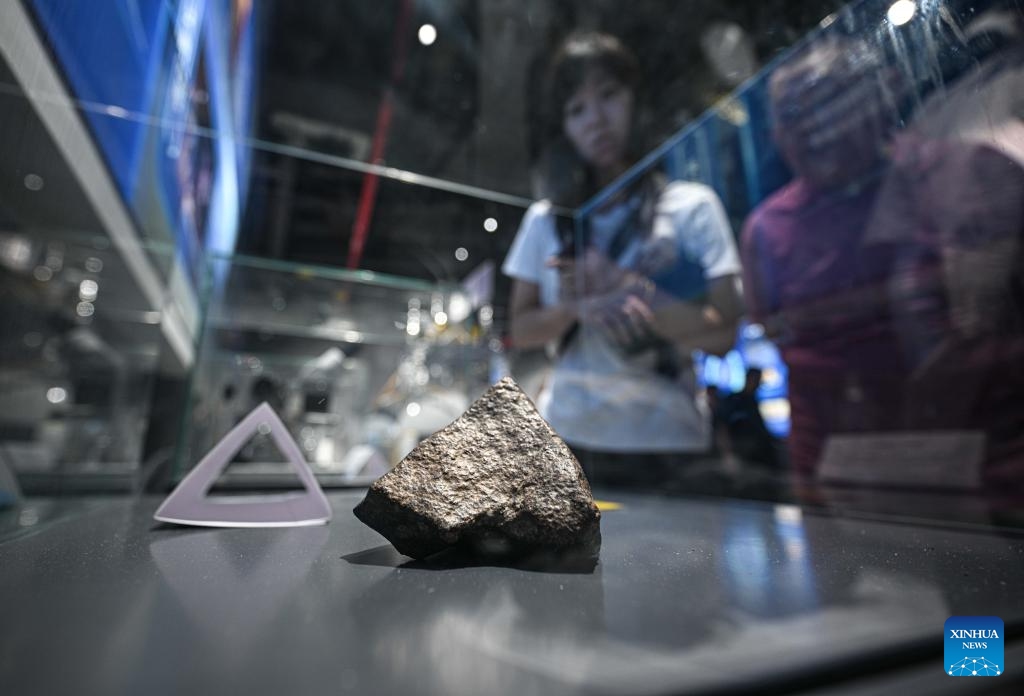 People watch a meteorite displayed at the Wenchang Aerospace Science and Education Center in Wenchang, south China's Hainan Province, Oct. 7, 2025. The upgrade project of the Wenchang Aerospace Science and Education Center is nearing completion. In preparation for its official opening, the center is open to the public free of charge for a limited time, allowing visitors to experience its operation and services firsthand. Following the renovation, the exhibition now features immersive experiences in aerospace history, rocket launches, space science and future exploration. (Xinhua/Pu Xiaoxu)