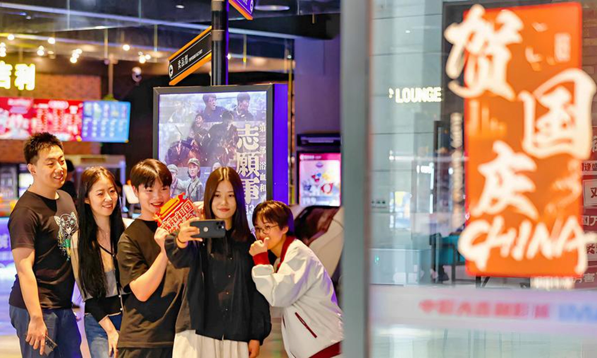 People take selfies with a movie poster at a cinema in north China's Tianjin, Oct. 4, 2025. (Photo by Du Penghui/Xinhua)