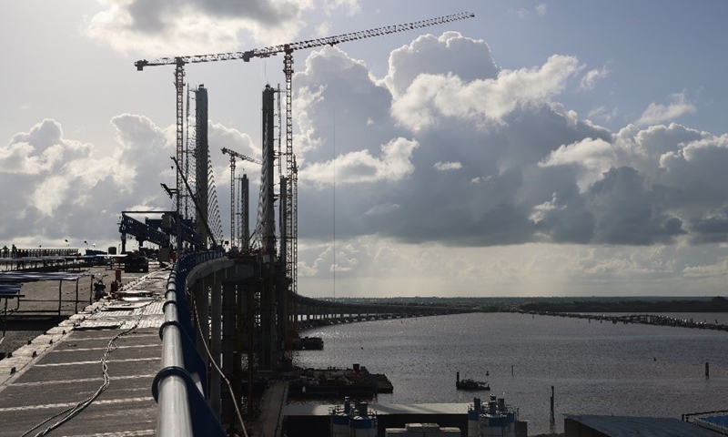 The New Demerara River Bridge is under construction, which is a sharp contrast to the old floating bridge (right). Photo: Shi Yuanhao