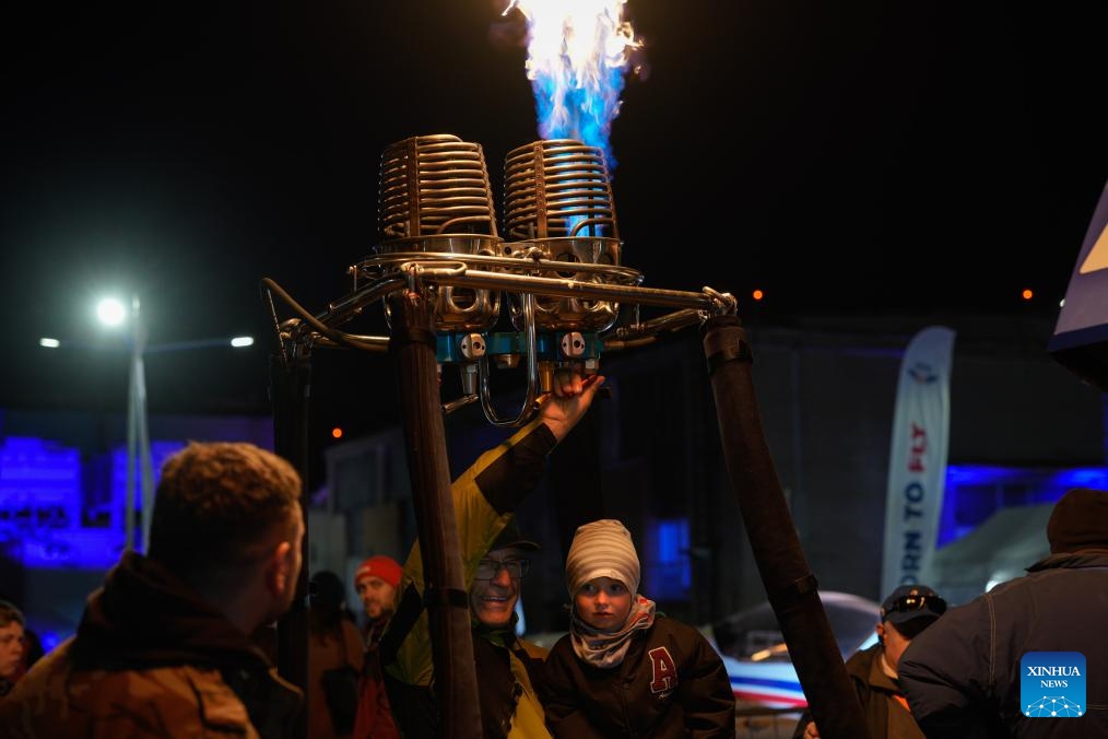 People watch a hot-air balloon burner demonstration during an aviation night event in Warsaw, Poland, Oct. 10, 2025. (Photo: Xinhua)