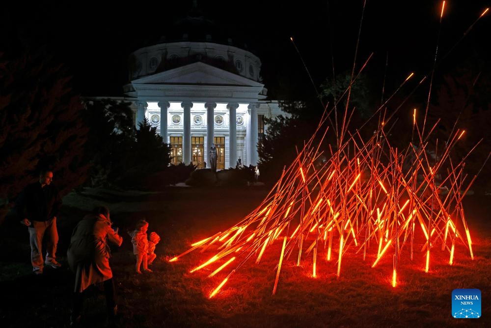 People take pictures next to a light art installation in front of Romanian Athenaeum during the Spotlight Festival in Bucharest, Romania, Oct. 10, 2025. (Photo: Xinhua)